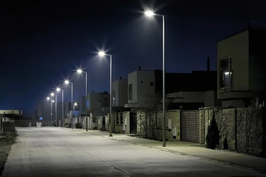 Postes de luz rectos de ORBE - Postes Metalicos con luminarias LED blancas que proporcionan una iluminación segura y uniforme en una calle de un condominio moderno por la noche.